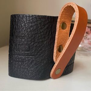 Portland Leather mug holder in pebbled black leather with a tan leather handle.